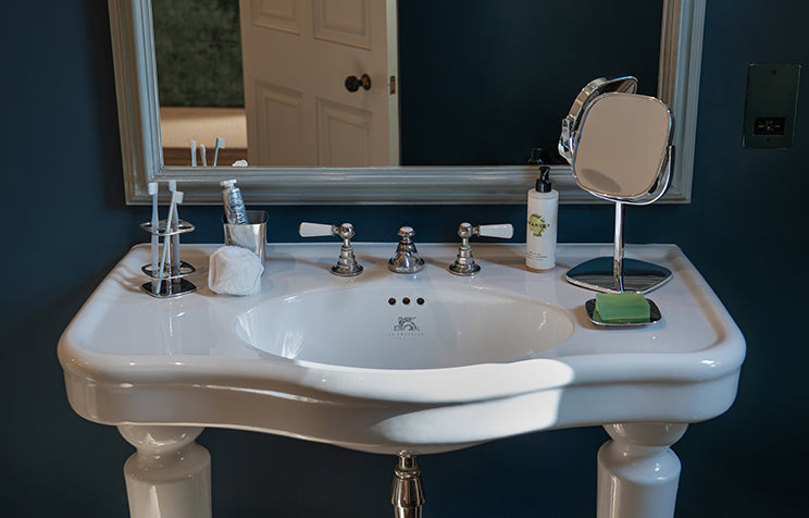 Bathroom sink with mirror and toiletries on a blue wall.
